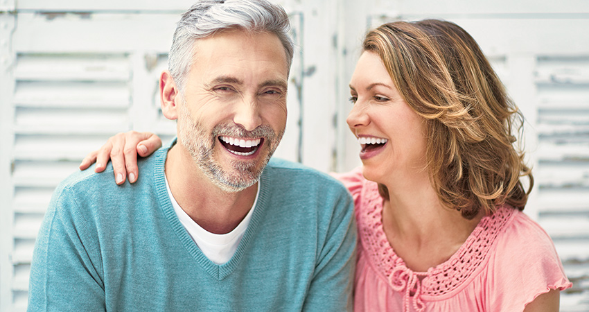 Older couple enjoying each other's company while smiling to reveal their dental veneers