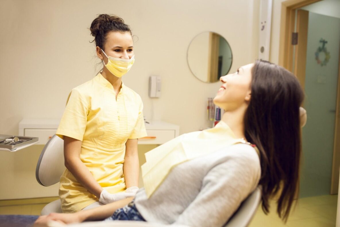 Dental hygienist consulting with a female patient during a dental checkup in clinic